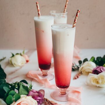 close up image of three tall glasses filled with hibiscus syrup, sparkling water and cream for hibiscus italiann soda