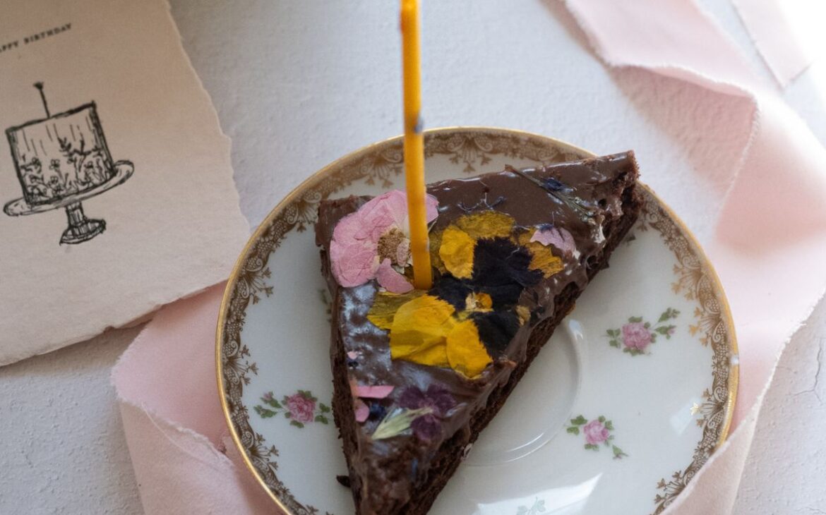 a piece of chocolate cake with a lit candle on a plate