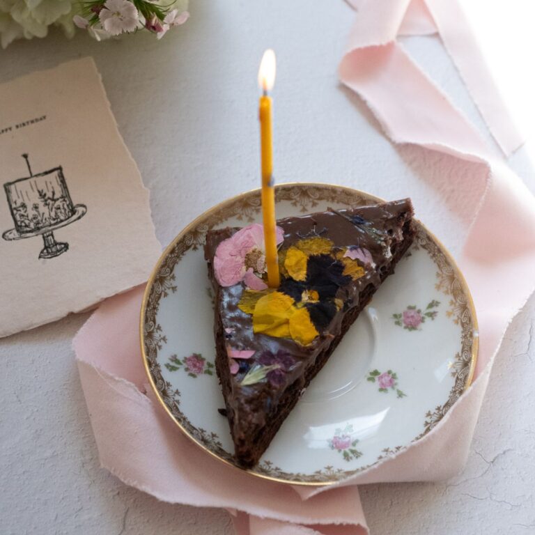 a piece of chocolate cake with a lit candle on a plate