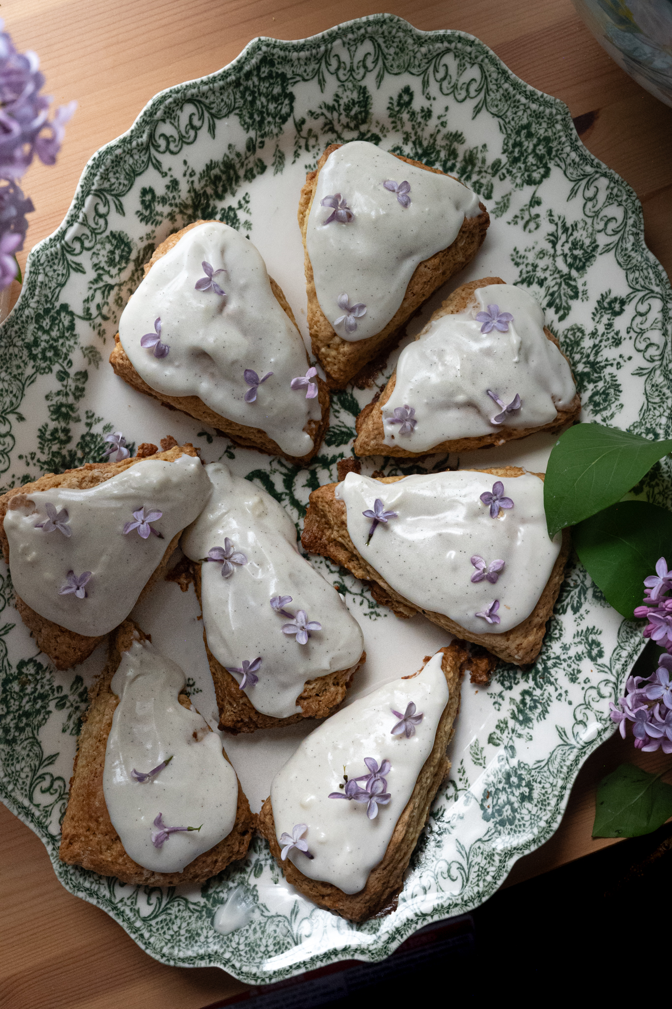 a plate of pastries with white frosting and purple flowers