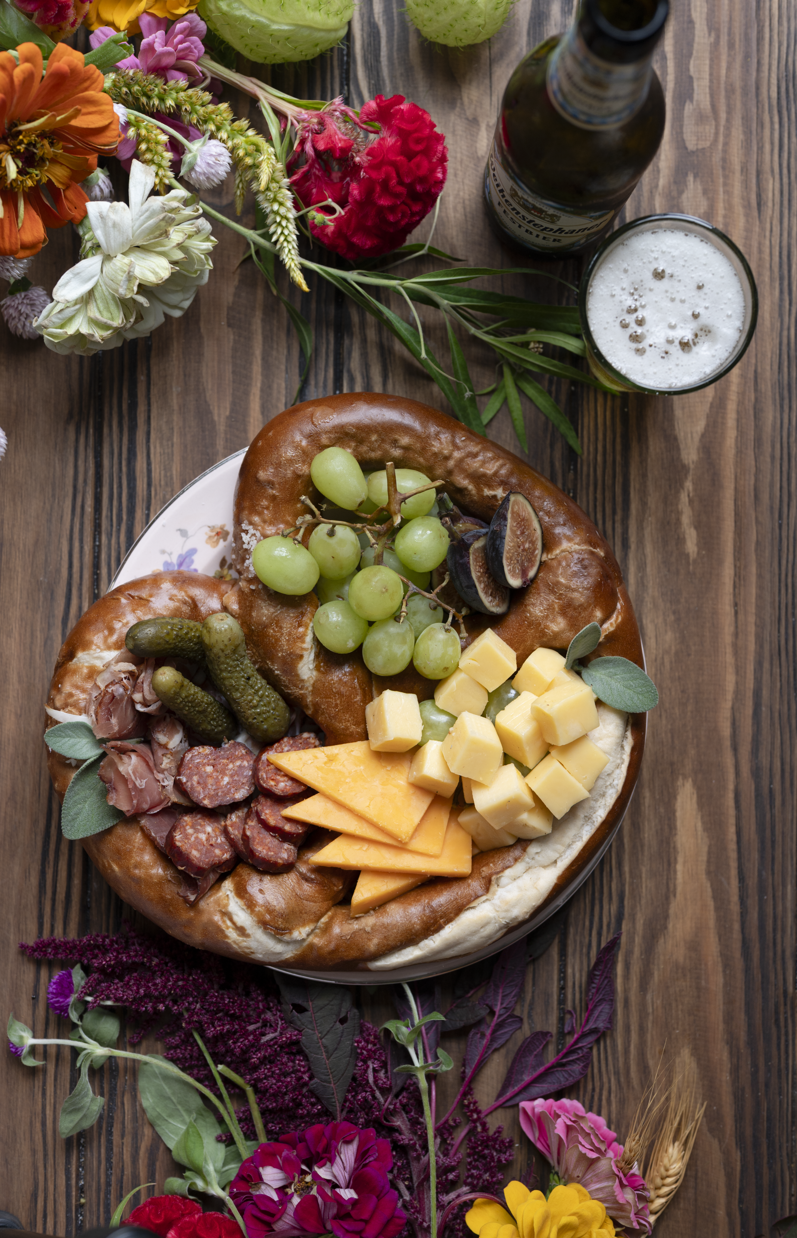 overhead shot of big Bavarian soft pretzel with fruit, meat and cheese for a soft pretzel charcuterie for Oktoberfest